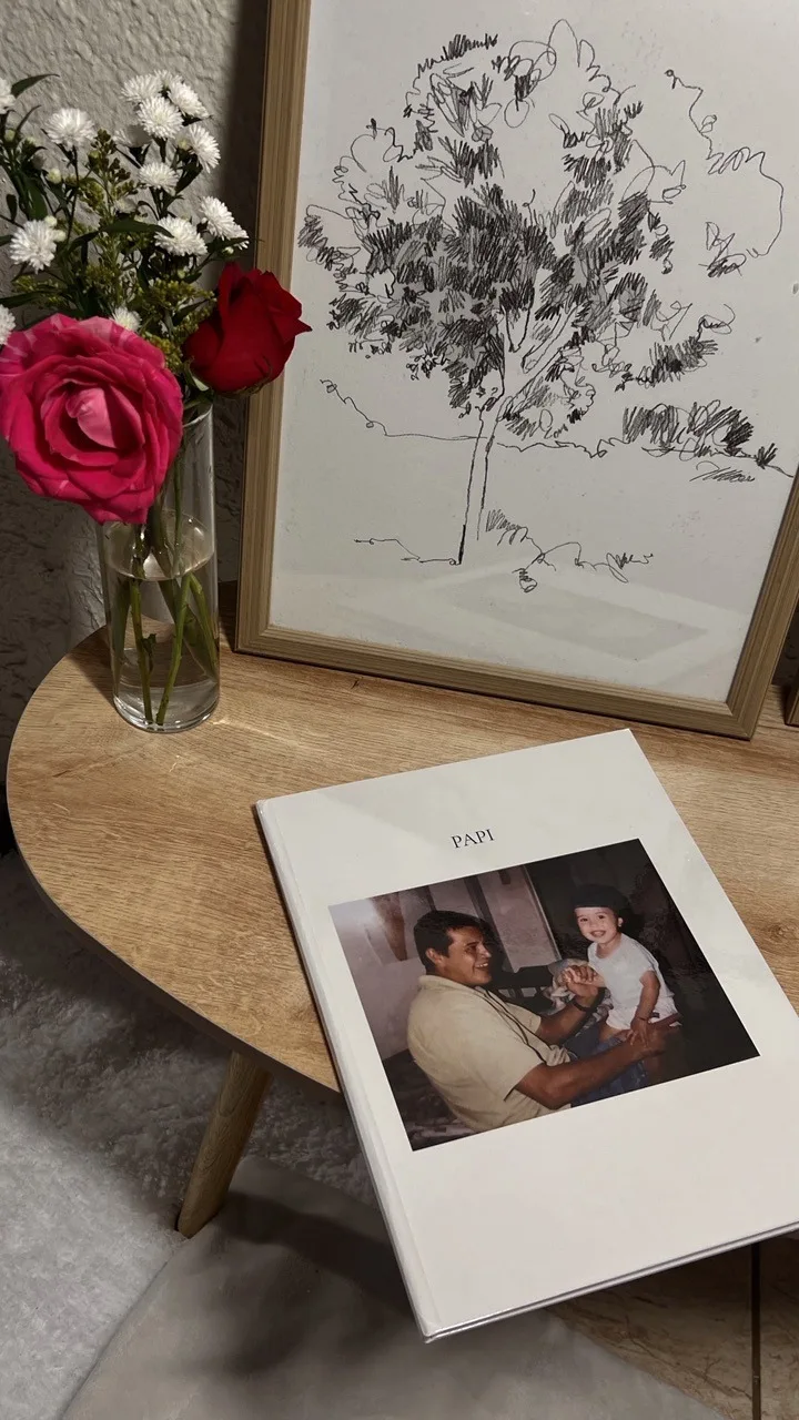 Photobook «Papá» de Alma Libre sobre una mesa de madera, junto a flores y un cuadro.